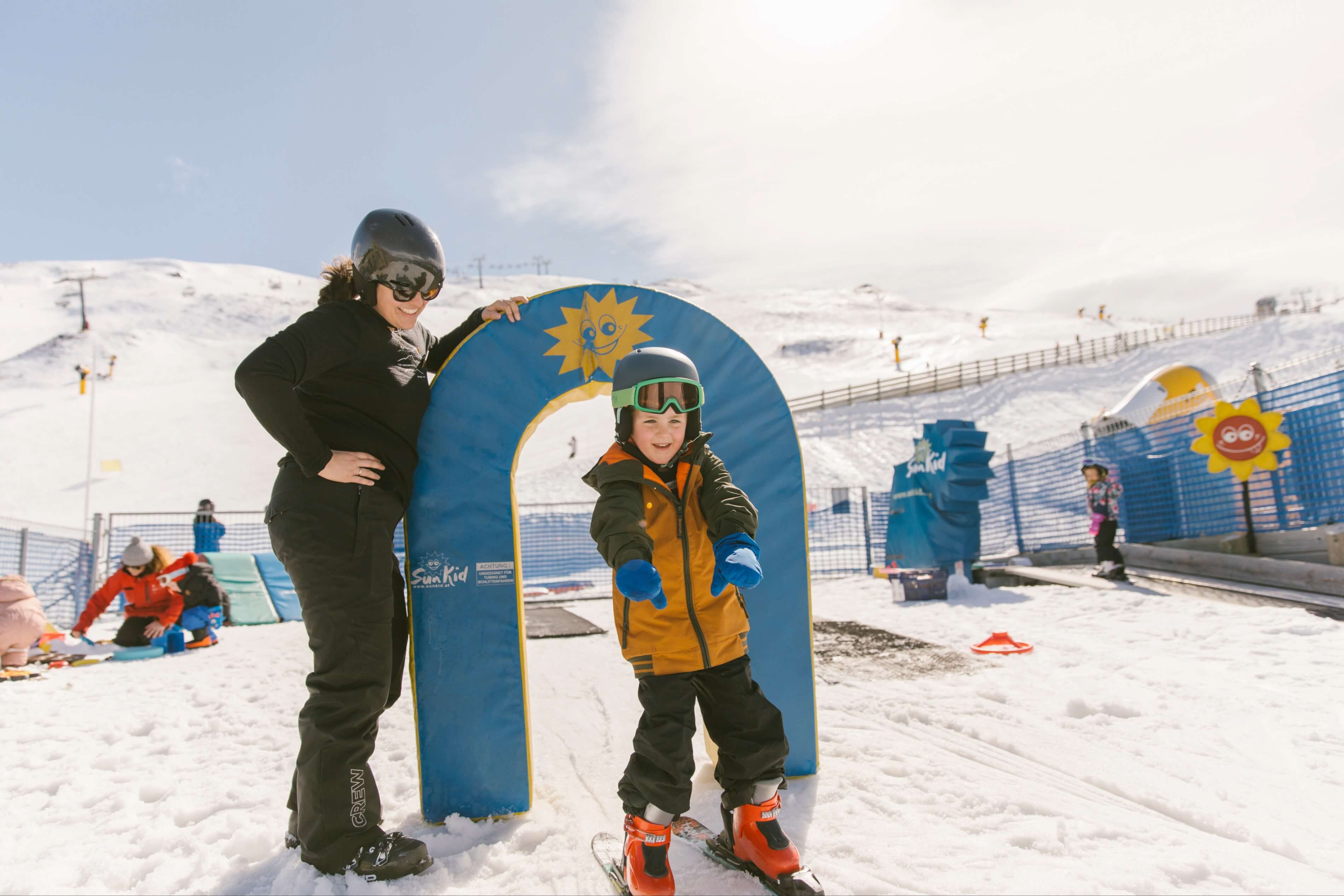 Young boy skiing down gentle beginners ski slope, smiling and laughing.