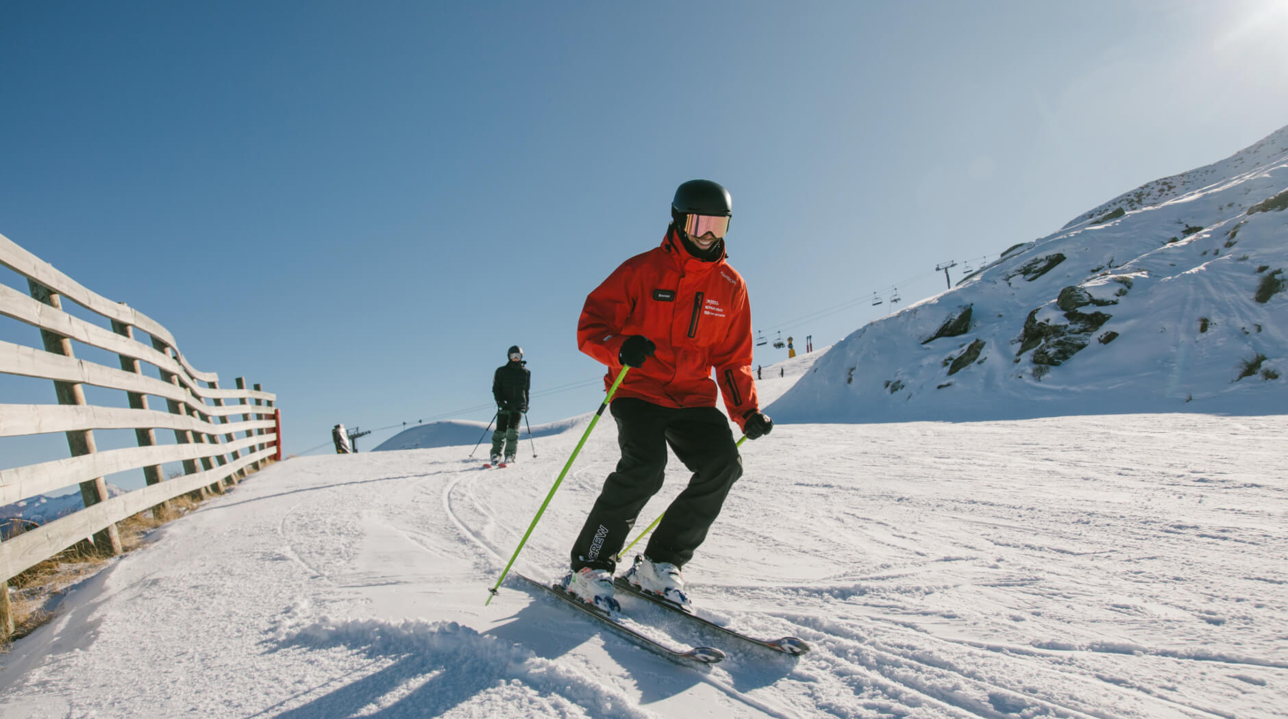 Ski instructor demonstrating a turn during a lesson on a groomed slope at Mt Hutt ski field