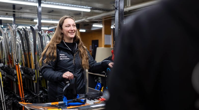 Staff member assisting with snowboard equipment in a rental shop at Mt Hutt