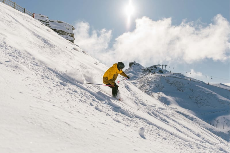 Person skiing down steep slope on a bluebird day.